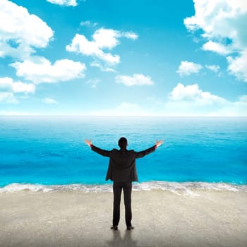Successful business man on the beach with blue sky background