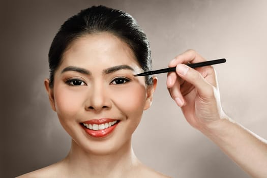 Beautiful asian woman doing makeup over blur background
