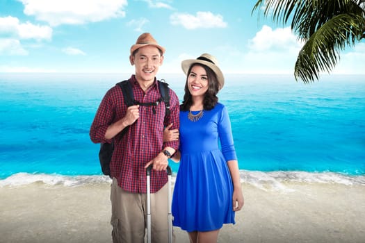 Couple asian tourist standing on the beach with blue sky background