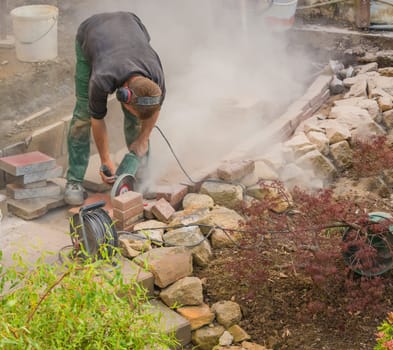 Man cuts stone slabs,concrete slab with an electric grinding machine.
