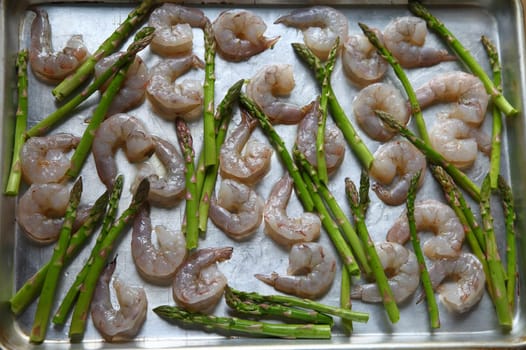 Raw shrimp and asparagus with olive oil before cooking in oven