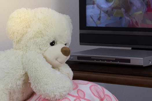 Teddy leans on the sofa and watches TV.