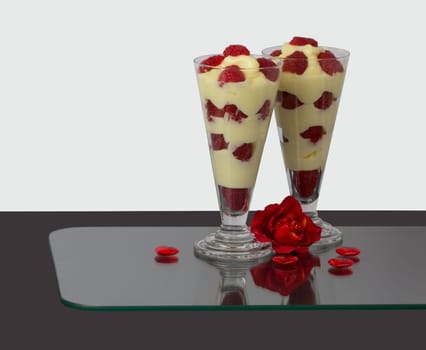 Two glasses with raspberry-vanilla cream and roses décor.