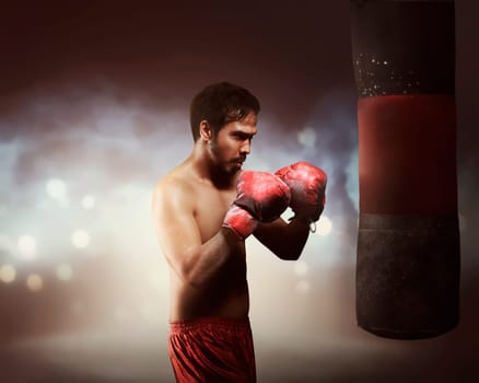 Masculine asian boxer man exercising with punching bag in light flashes