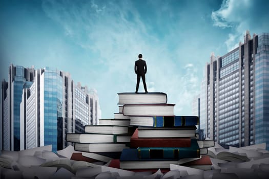 Business man standing on the top of books looking the city