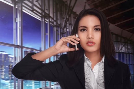 Asian business woman calling on the phone late at night to her business partner