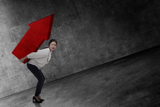 Asian business woman lifting heavy arrow. Business challenge concept