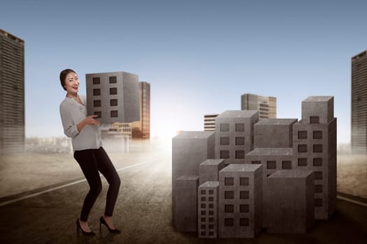 Asian business woman lifting block of city. Building city concept