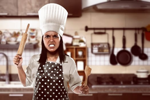 Angry asian woman chef over over clean kitchen background