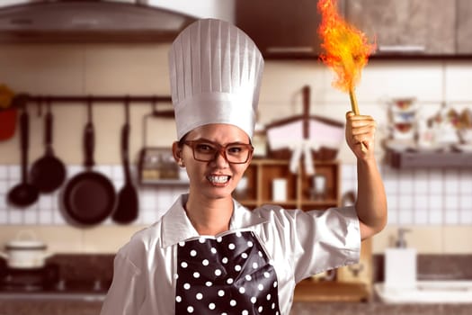 Portrait of angry young woman chef over kitchen background