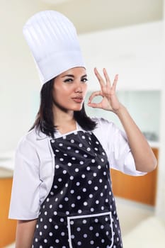 Portrait of young woman chef over kitchen background