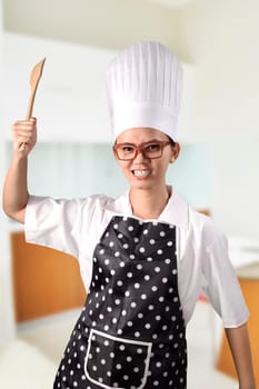 Portrait of young woman chef over kitchen background