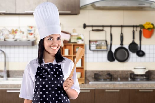 Portrait of young woman chef over kitchen background