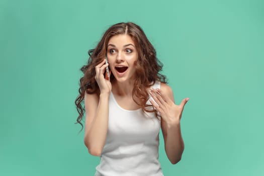 The young woman's portrait with happy emotions and mobile phone at studio