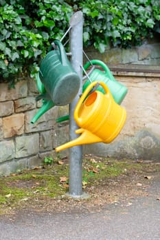 Watering cans for watering on a post in the cemetery