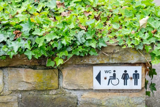 Sign WC for disabled,women and men on a stone wall