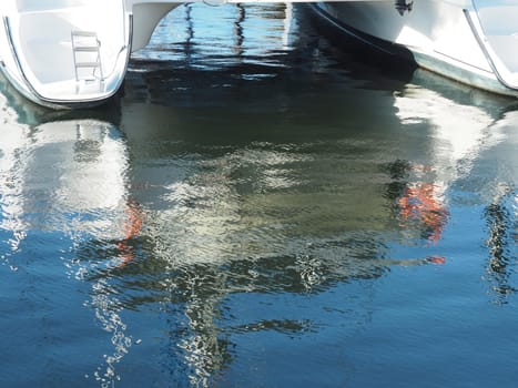 Reflections of a modern catamaran in a luxury marina