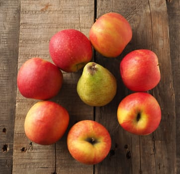Red apples and green pear on a rustic wooden table