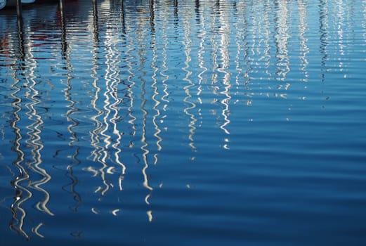 Reflections of sailing boats on the water in amarina at sunset
