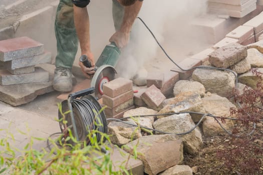 Man cuts stone slabs,concrete slab with an electric grinding machine.