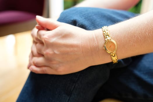 Folded hands and arm with gold watch hold one foot