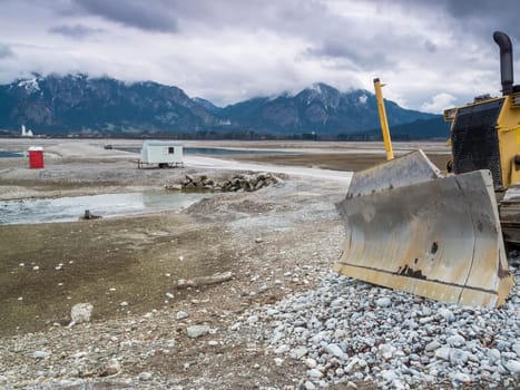 Shield of a bulldozer in the drained Forggensee near Füssen / Bavaria. The Forggensee is fed by thawing snow from the high Alps and is a reservoir for sedimentary rocks. In spring,the lake is emptied to remove the sedimentary rock. In summer,the lake has returned to its normal water level and is navigated by excursion boats.