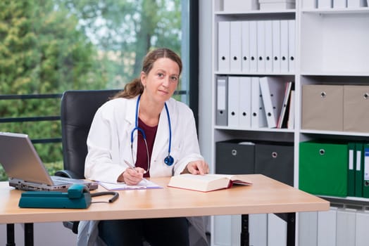 young female family doctor in her office is looking in to the camera