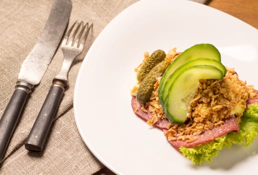 Danish specialties and national dishes, high-quality open sandwich. Salami with crispy onion, remoulade and cucumber served on a plate ready for eating