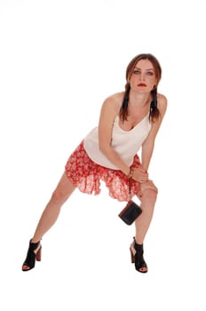 A gorgeous young woman bending forwards is shorts and high heels.looking serious, isolated for white background..