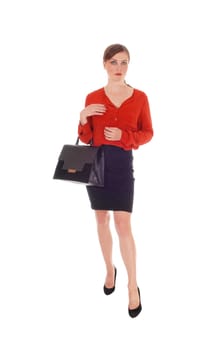 A gorgeous young business woman standing in a red blouse and black .skirt, holding her purse, isolated for white background..