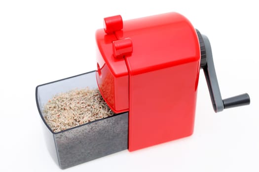 Red pencil sharpener with pencil trash on white background