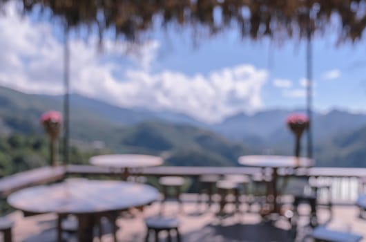 Blurred image of outdoor terrace cafe and restaurant tables with mountain view background