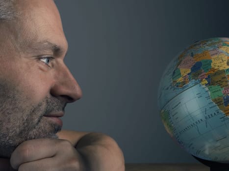 Travel or vacation concept with a man looking at a globe, close up shot