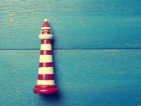 Small lighthouse on a rustic wooden background using as vacation card