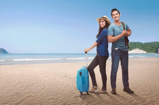 Happy couple asian tourist with luggage enjoying trip on tropical beach