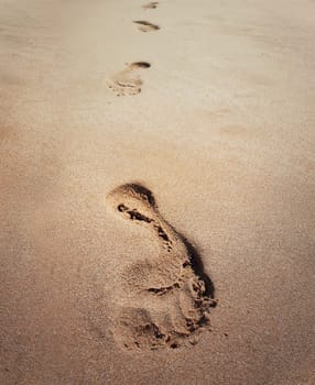 Closeup of footprints in sand at the beach. Holiday travel concept