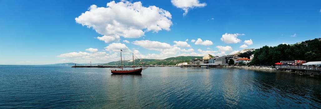 Clear morning panoramic view with a sail boat floating in the Black Sea, Balchik city, Bulgaria. Summer vacation background. Joy, happiness and recreation concept