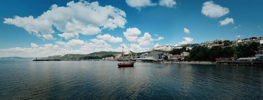 Clear morning panoramic view with a sail boat floating in the Black Sea, Balchik city, Bulgaria. Summer vacation background. Joy, happiness and recreation concept