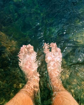 Close up of male legs in the clear sea water. Summer vacation, resting and recreation concept