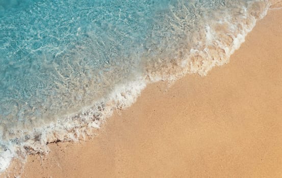 Soft foaming wave of blue sea on a sand beach. Summer vacation background, holiday recreation concept