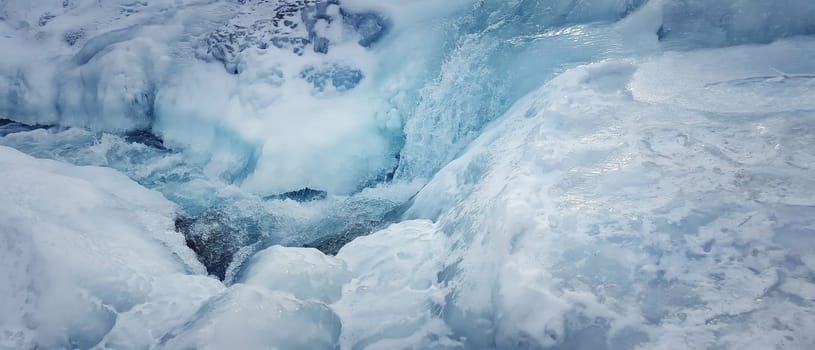 Abstract frozen river background, very cold winter, as blue water flows through the snowy ice.