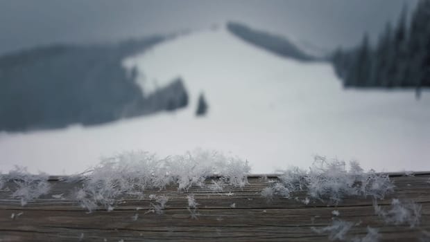Wooden table covered with soft snowflakes on a beutiful mountains background