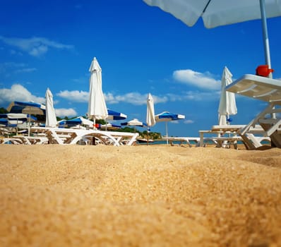 Group of sunbeds and umbrellas in the beach near the sea. Summer vacation background