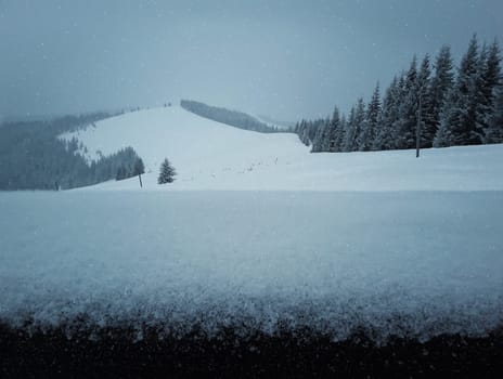 Wooden fence covered with snow on a beautiful mountains background