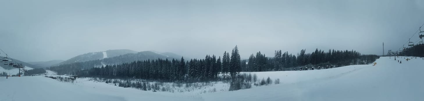 Panoramic view over the Carpathian mountains in Ukraine.Gondola lift on ski resort at windy winter day and snow covered fir trees.