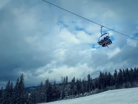 Winter cableway with people and downhill covered in snow with prints of ski in Carpathians mountains.