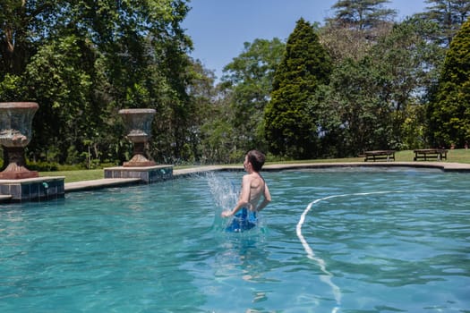 Boy running jumping diving into home  swimming pool summer playtime
