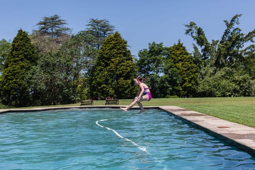 Girl running jumping into home swimming pool summer playtime