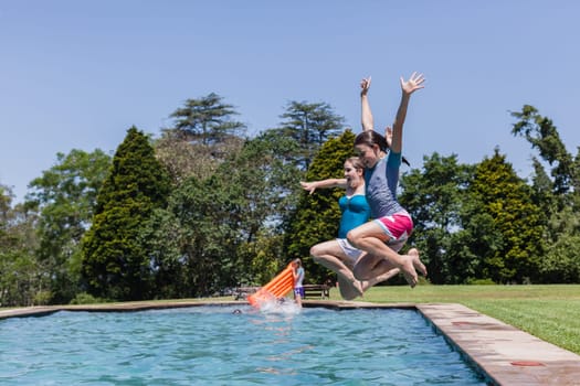 Girls running jumping into home  swimming pool summer playtime