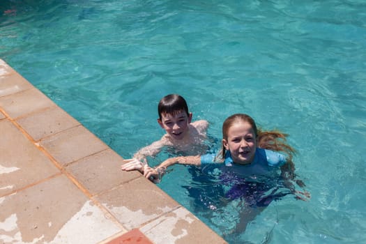 Girl Boy playing in swimming pool home summer